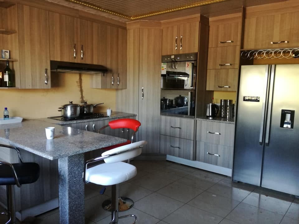 Luxury custom kitchen with wood-grain units and breakfast bar by PZN Designs